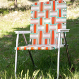 Orange and teal lawn chair in a geometric pattern on a grass field.
