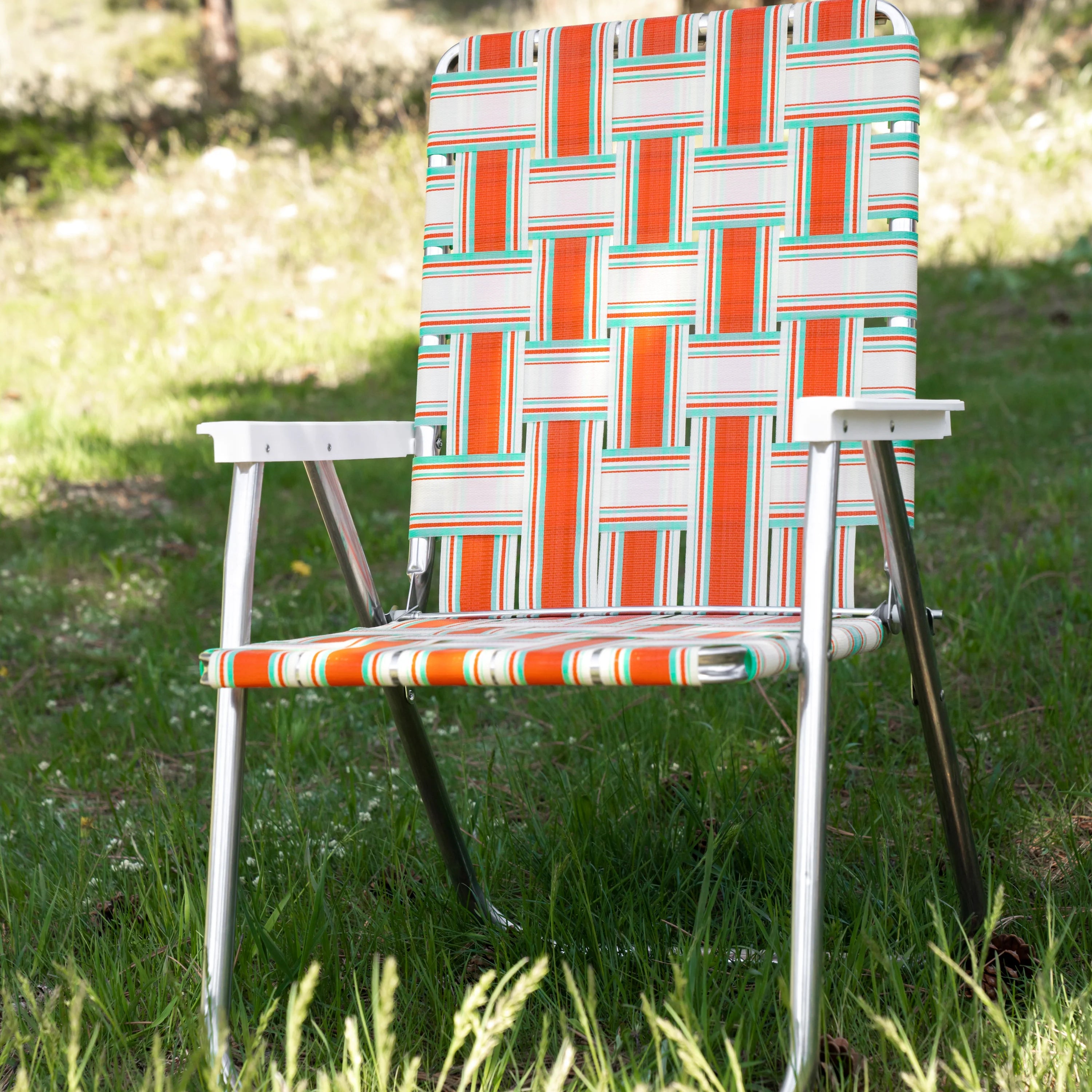 Orange and teal lawn chair in a geometric pattern on a grass field.