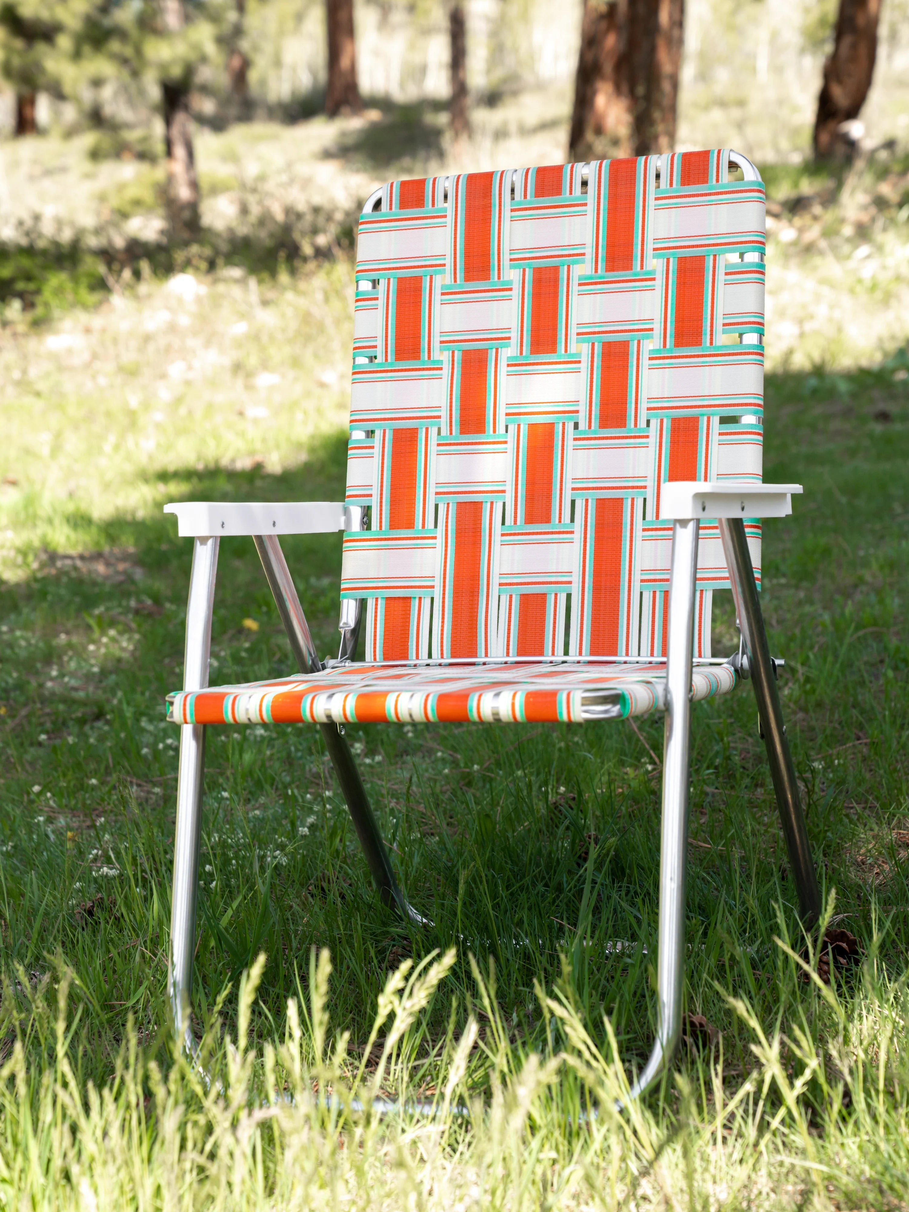Orange and teal lawn chair in a geometric pattern on a grass field.
