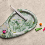 Marble-patterned smoking accessory with colorful incense cones on a beige surface