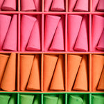 Colorful incense cones in pink, orange, and green arranged in a grid.