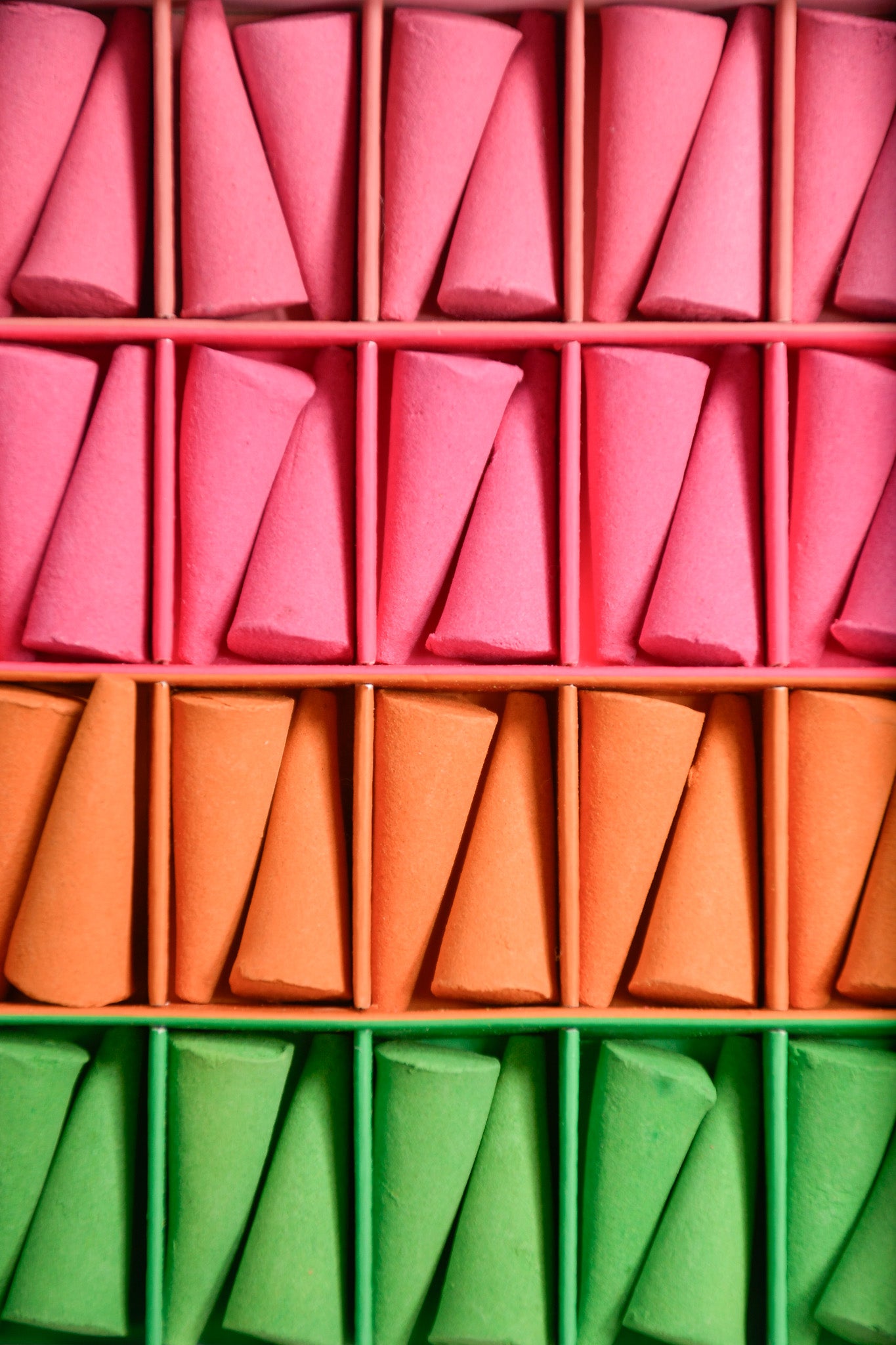 Colorful incense cones in pink, orange, and green arranged in a grid.